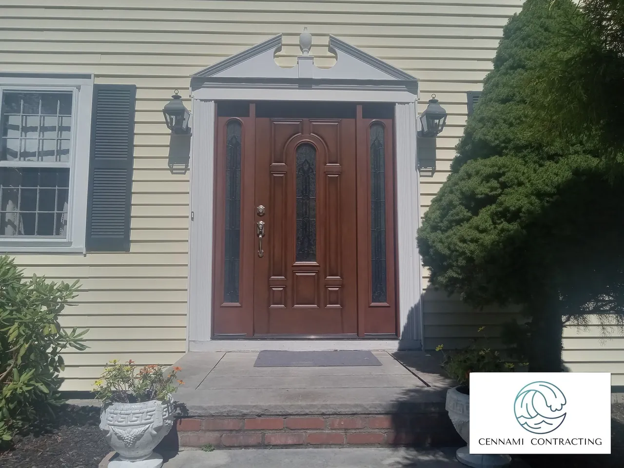 Brown front door with sidelights under a decorative pediment