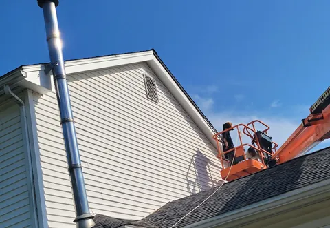 Crew working from a lift on a house chimney and siding